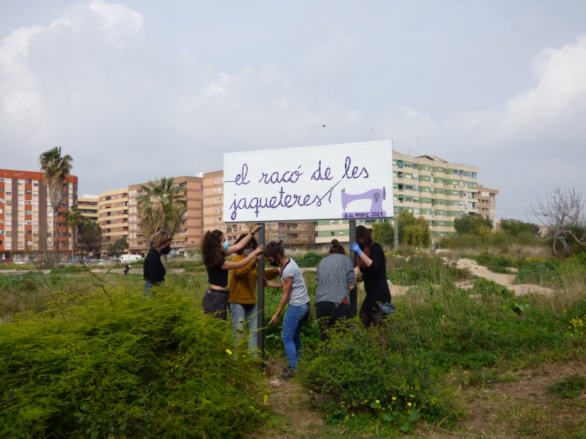 Unas mujeres levantan el cartel del 'Racó de les jaqueteres' en Benimaclet