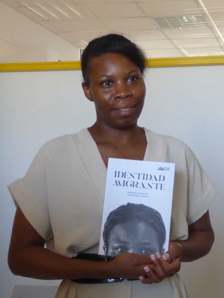 Una de las protagonistas del libro 'Identidad migrante', Yolanda Campo, posa con la portada de la obra, que lleva por portada su imagen
